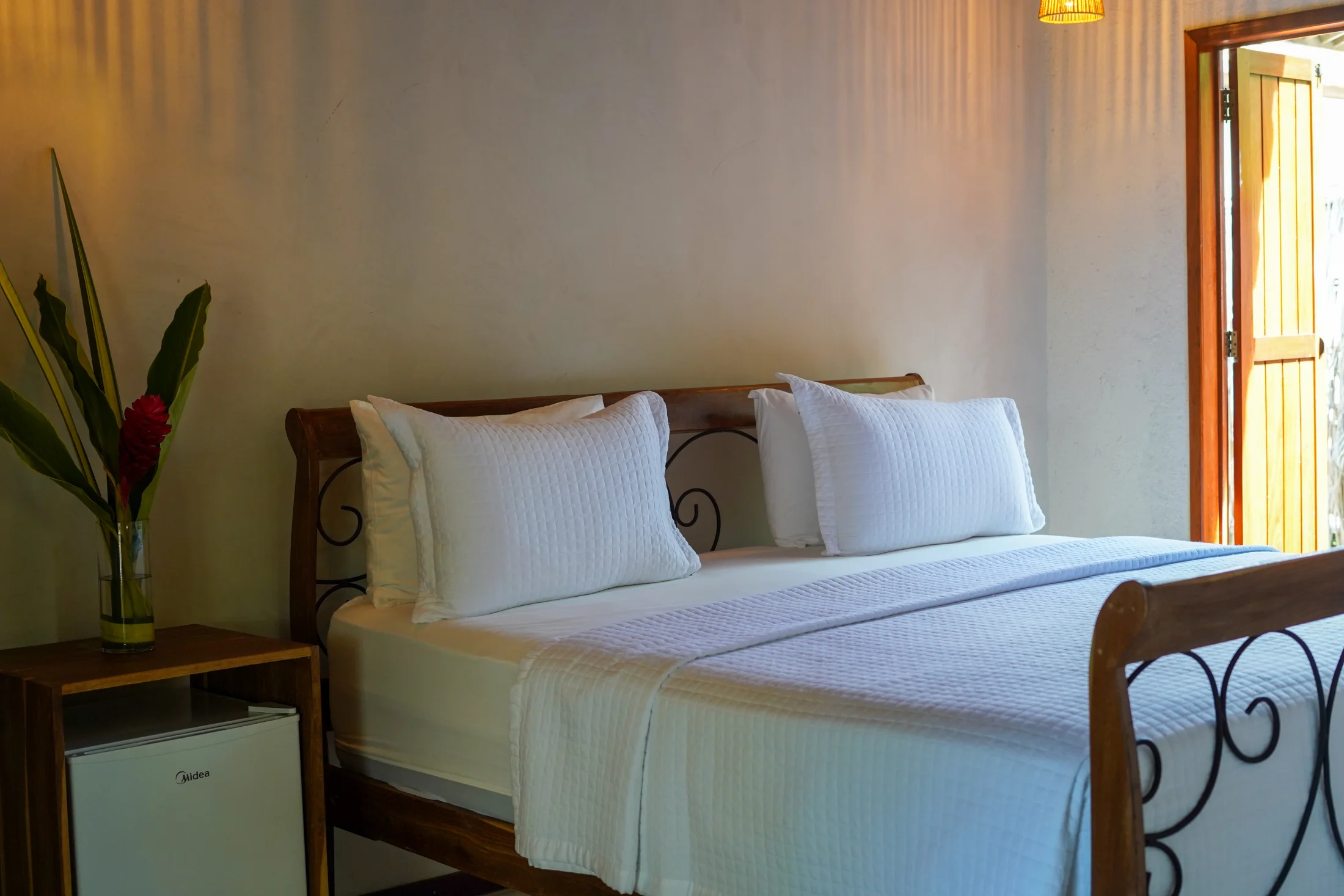 Cama king-size e iluminação natural no Bangalô Jabuticaba